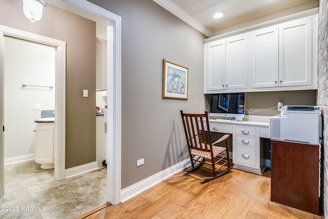 office space featuring ornamental molding, built in desk, and light wood-type flooring