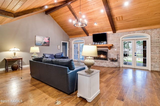 living room with wood ceiling, hardwood / wood-style floors, high vaulted ceiling, a brick fireplace, and french doors