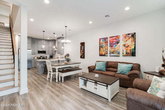 living room with light hardwood / wood-style floors and an inviting chandelier