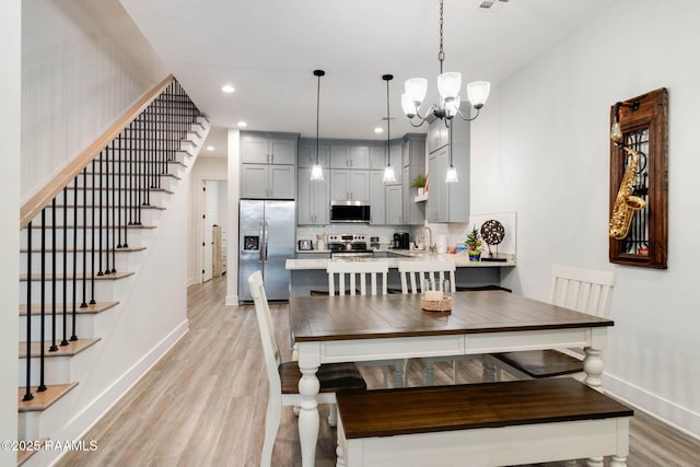 dining area with light hardwood / wood-style floors, sink, and a chandelier