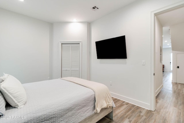 bedroom with light hardwood / wood-style floors and a closet