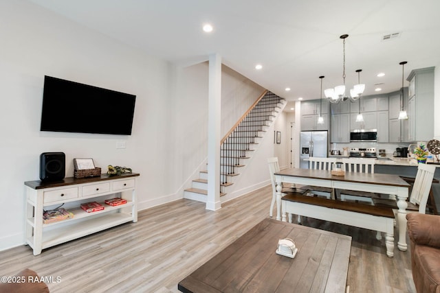 living room with light hardwood / wood-style flooring and a notable chandelier