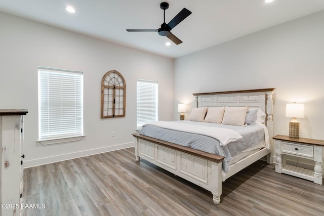 bedroom featuring hardwood / wood-style floors, ceiling fan, and multiple windows