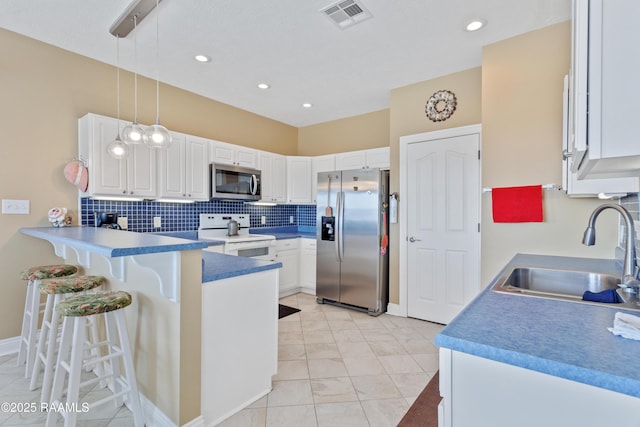 kitchen featuring sink, stainless steel appliances, hanging light fixtures, and white cabinets