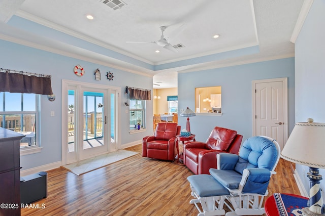 living room featuring crown molding, a tray ceiling, light hardwood / wood-style flooring, and ceiling fan