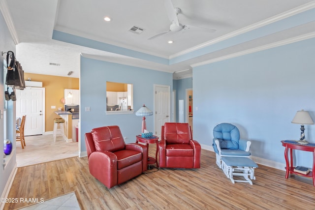 living room with a raised ceiling, ceiling fan, ornamental molding, and light hardwood / wood-style floors