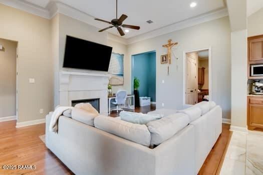 living room featuring ceiling fan, crown molding, and light hardwood / wood-style floors