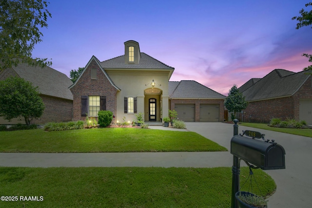 208 Rue De Frejus, Broussard, LA 70518 - view of front facade featuring a garage, a front yard, concrete driveway, brick siding, and stucco siding