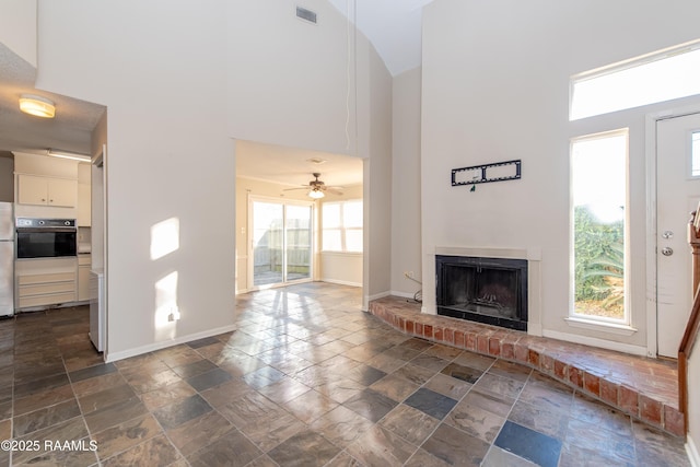 unfurnished living room with ceiling fan, a brick fireplace, and high vaulted ceiling