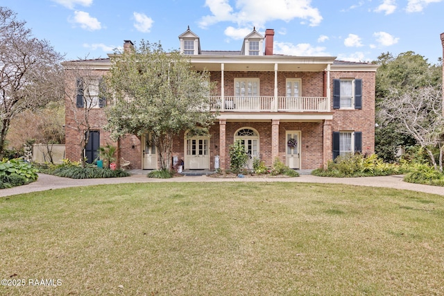 view of front facade featuring a front yard, a balcony, and covered porch