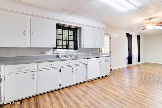 kitchen featuring sink, white dishwasher, ornamental molding, light hardwood / wood-style floors, and white cabinets