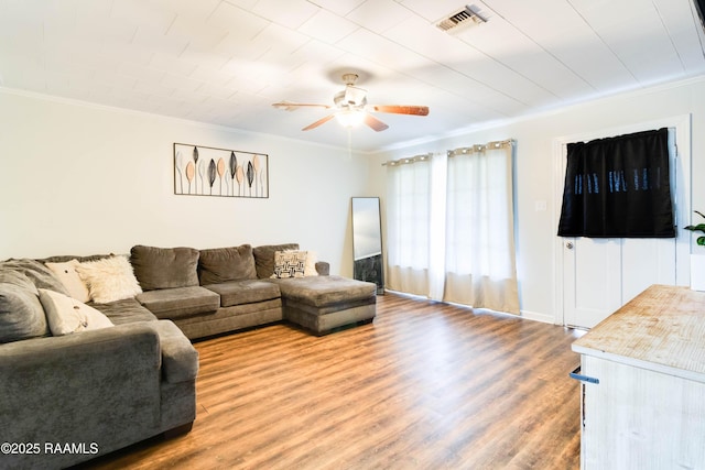 living room with wood-type flooring, ornamental molding, and ceiling fan