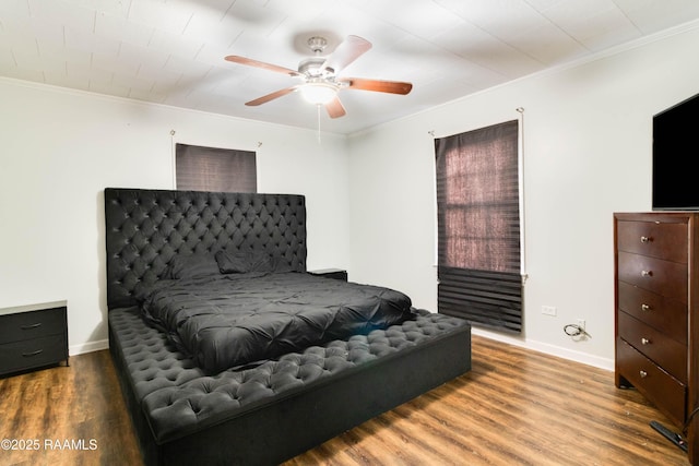 bedroom featuring dark wood-type flooring, ornamental molding, and ceiling fan