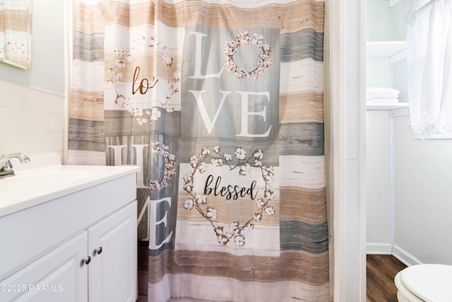 bathroom featuring vanity, hardwood / wood-style floors, toilet, and tile walls