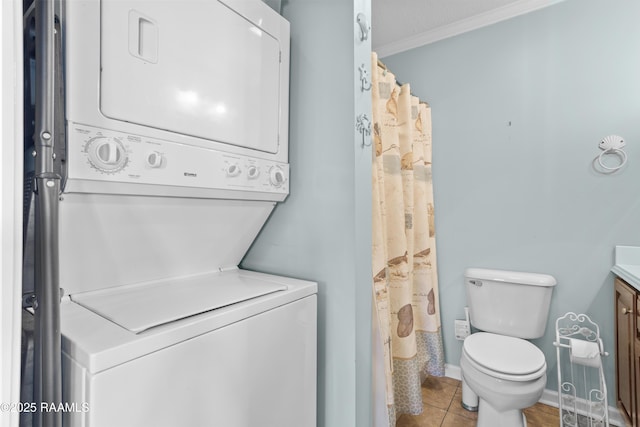 washroom featuring crown molding, stacked washing maching and dryer, and light tile patterned floors