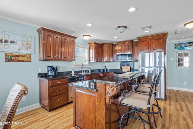 kitchen featuring crown molding, light wood-type flooring, stainless steel appliances, and a kitchen island