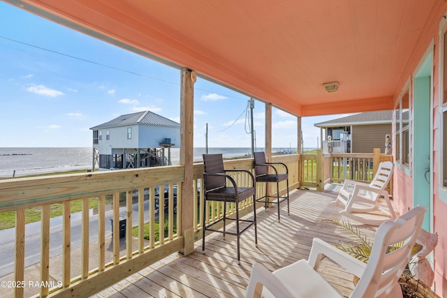 wooden terrace featuring a beach view and a water view