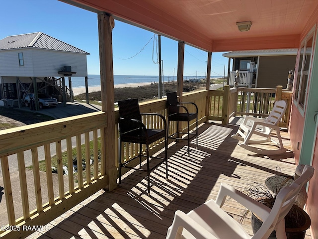 wooden terrace featuring a water view and a view of the beach