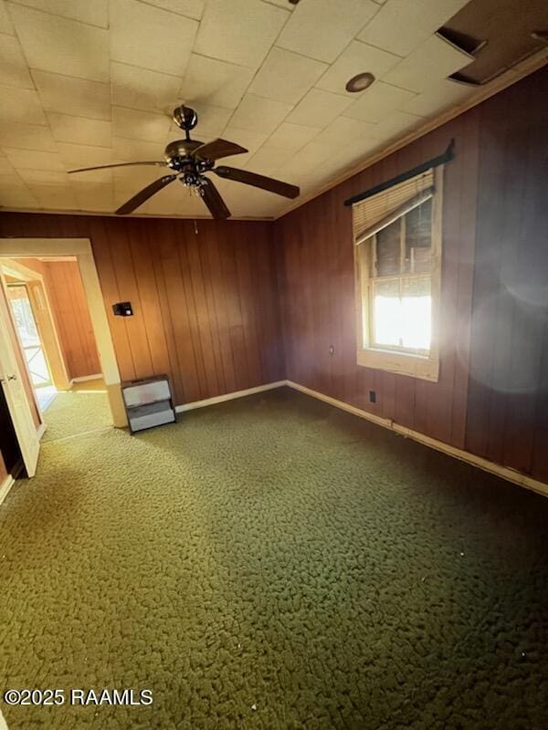 spare room featuring ceiling fan and wood walls