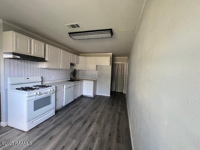 kitchen with white cabinetry, sink, dark hardwood / wood-style floors, white appliances, and decorative backsplash