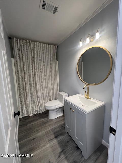 bathroom with ornamental molding, vanity, wood-type flooring, and toilet