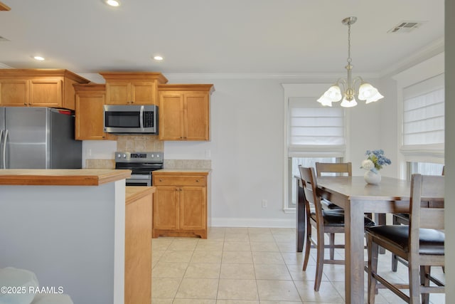 kitchen featuring tasteful backsplash, decorative light fixtures, ornamental molding, and stainless steel appliances