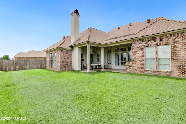 back of property with a lawn, ceiling fan, and a patio