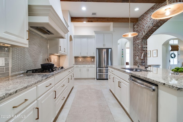 kitchen with sink, custom range hood, white cabinets, and appliances with stainless steel finishes