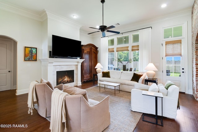 living room with ornamental molding, dark wood-type flooring, and ceiling fan