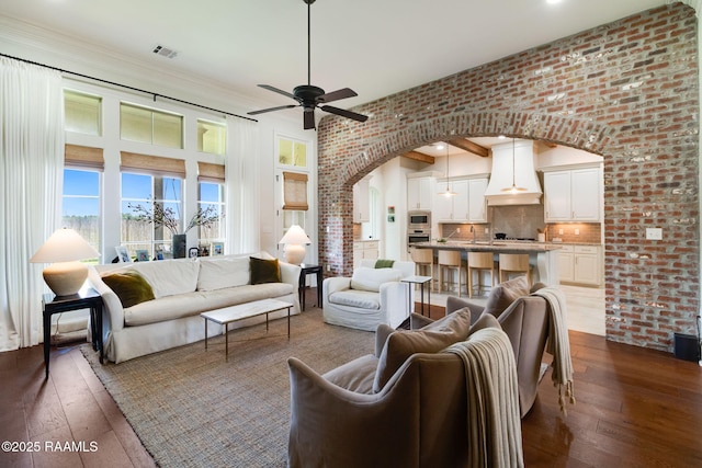 living room with brick wall, dark hardwood / wood-style flooring, and ceiling fan