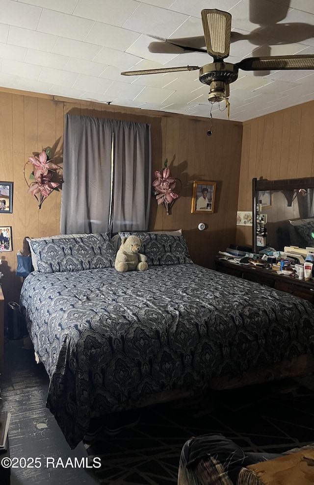 bedroom featuring ceiling fan and wooden walls