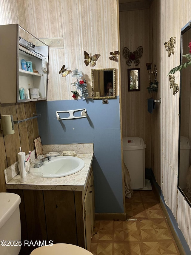 bathroom with toilet, vanity, and parquet floors