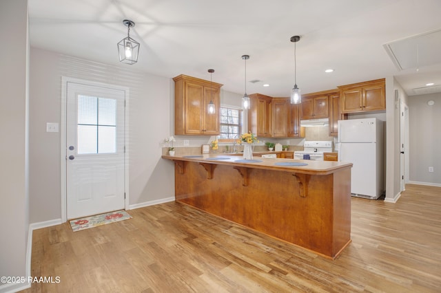 kitchen with kitchen peninsula, white appliances, light hardwood / wood-style floors, and pendant lighting