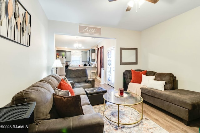 living room with light hardwood / wood-style flooring and ceiling fan with notable chandelier