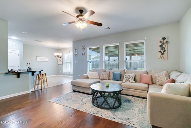 living room with hardwood / wood-style floors, ceiling fan with notable chandelier, and sink