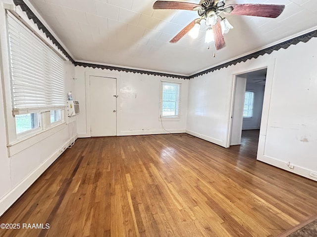 empty room with ceiling fan, a baseboard heating unit, plenty of natural light, and wood-type flooring