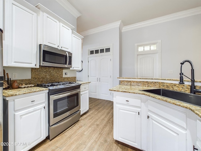 kitchen with crown molding, appliances with stainless steel finishes, sink, and white cabinets