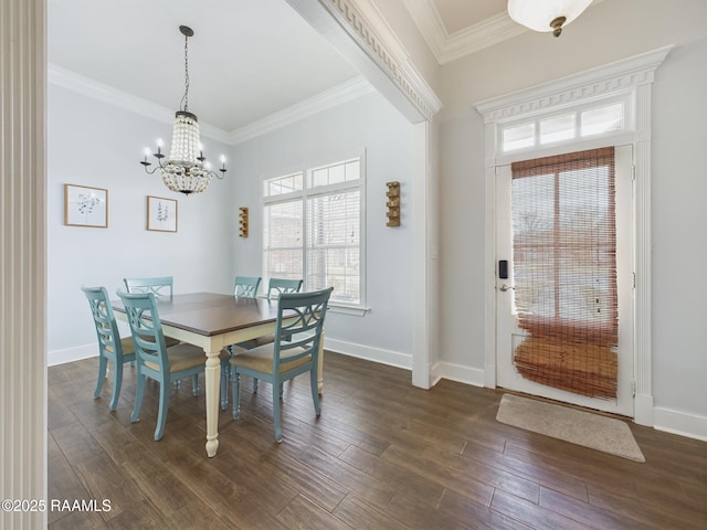 dining space featuring dark wood-type flooring, ornamental molding, and an inviting chandelier