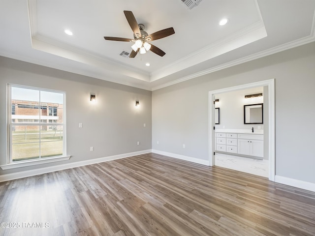 empty room featuring crown molding, light hardwood / wood-style flooring, ceiling fan, and a tray ceiling