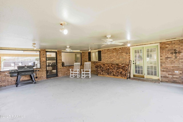 living room featuring brick wall, concrete floors, and ceiling fan