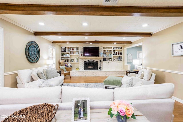 living room with a fireplace, hardwood / wood-style floors, built in shelves, crown molding, and beam ceiling