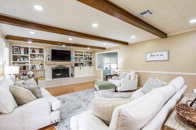 living room with beamed ceiling, hardwood / wood-style flooring, built in features, and a fireplace