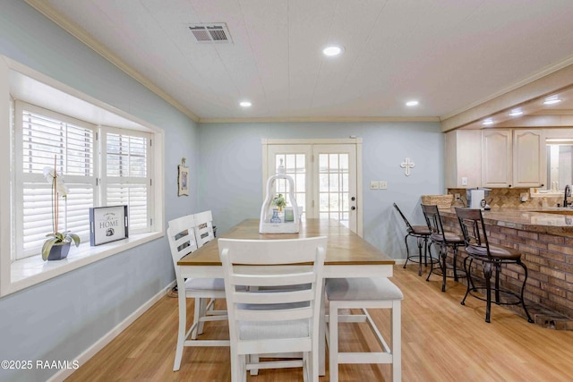 dining area with a wealth of natural light, light hardwood / wood-style floors, and crown molding