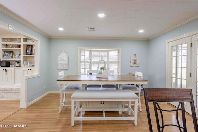 dining room featuring light hardwood / wood-style flooring, crown molding, and built in shelves