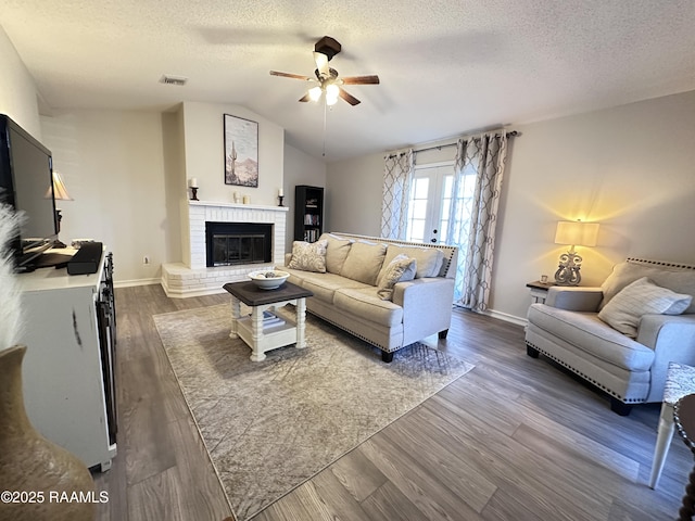 living room with a fireplace, a textured ceiling, and dark hardwood / wood-style floors