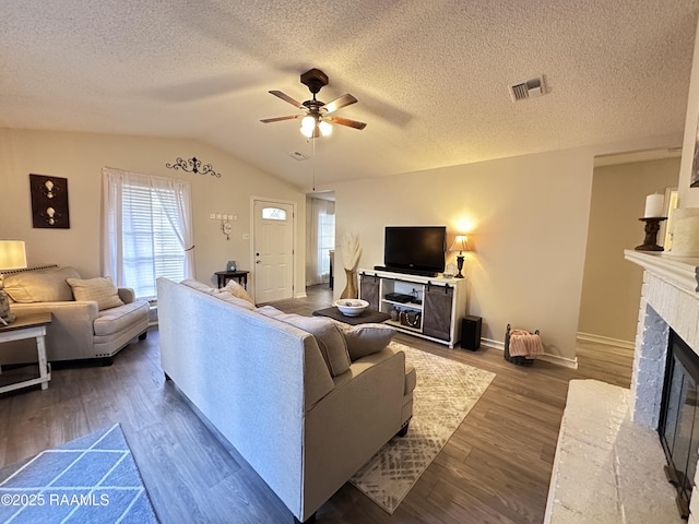 living room featuring a textured ceiling, lofted ceiling, wood-type flooring, ceiling fan, and a brick fireplace