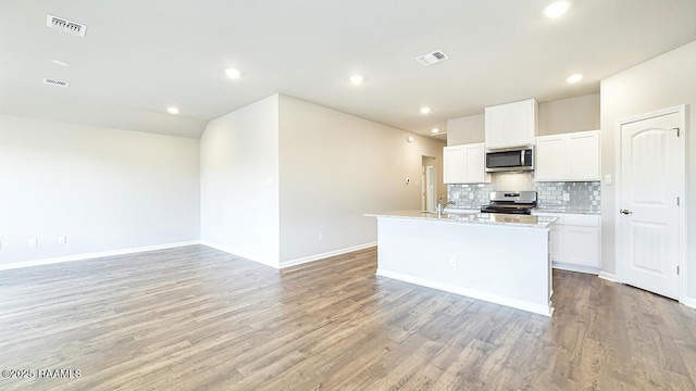 kitchen with stainless steel appliances, a center island with sink, white cabinets, and decorative backsplash