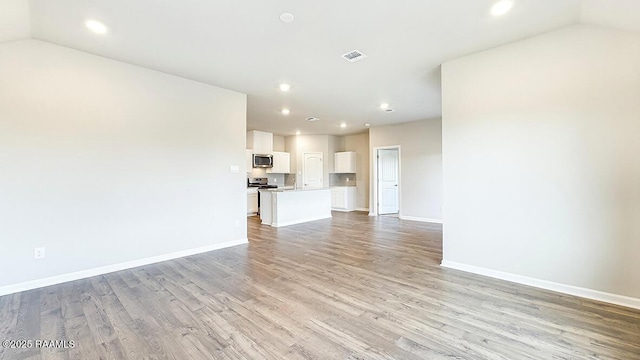 unfurnished living room featuring lofted ceiling and light wood-type flooring