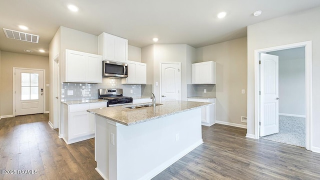 kitchen with light stone countertops, stainless steel appliances, an island with sink, white cabinets, and sink