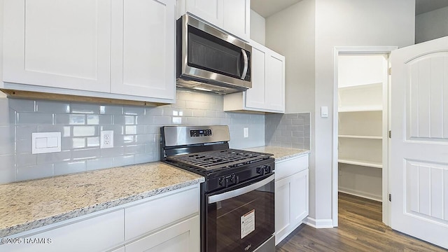 kitchen with stainless steel appliances, white cabinetry, dark hardwood / wood-style flooring, and light stone counters